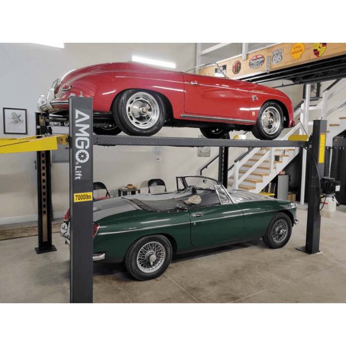 Two classic cars stacked on heavy-duty garage lift. 