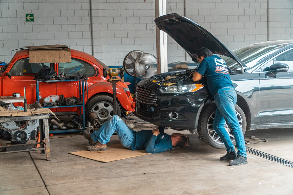 Two mechanics repairing cars in auto repair shop