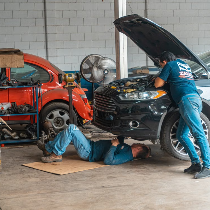 Two mechanics repairing cars in auto repair shop