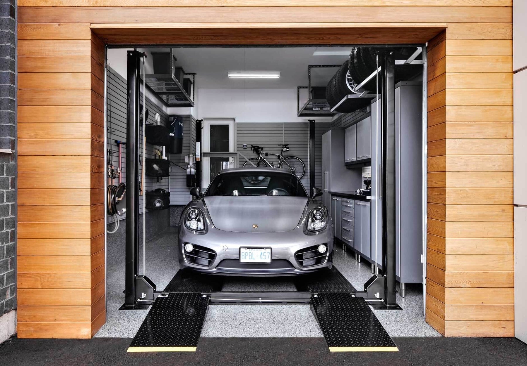 Modern garage with Porsche on lift and organized storage setup.