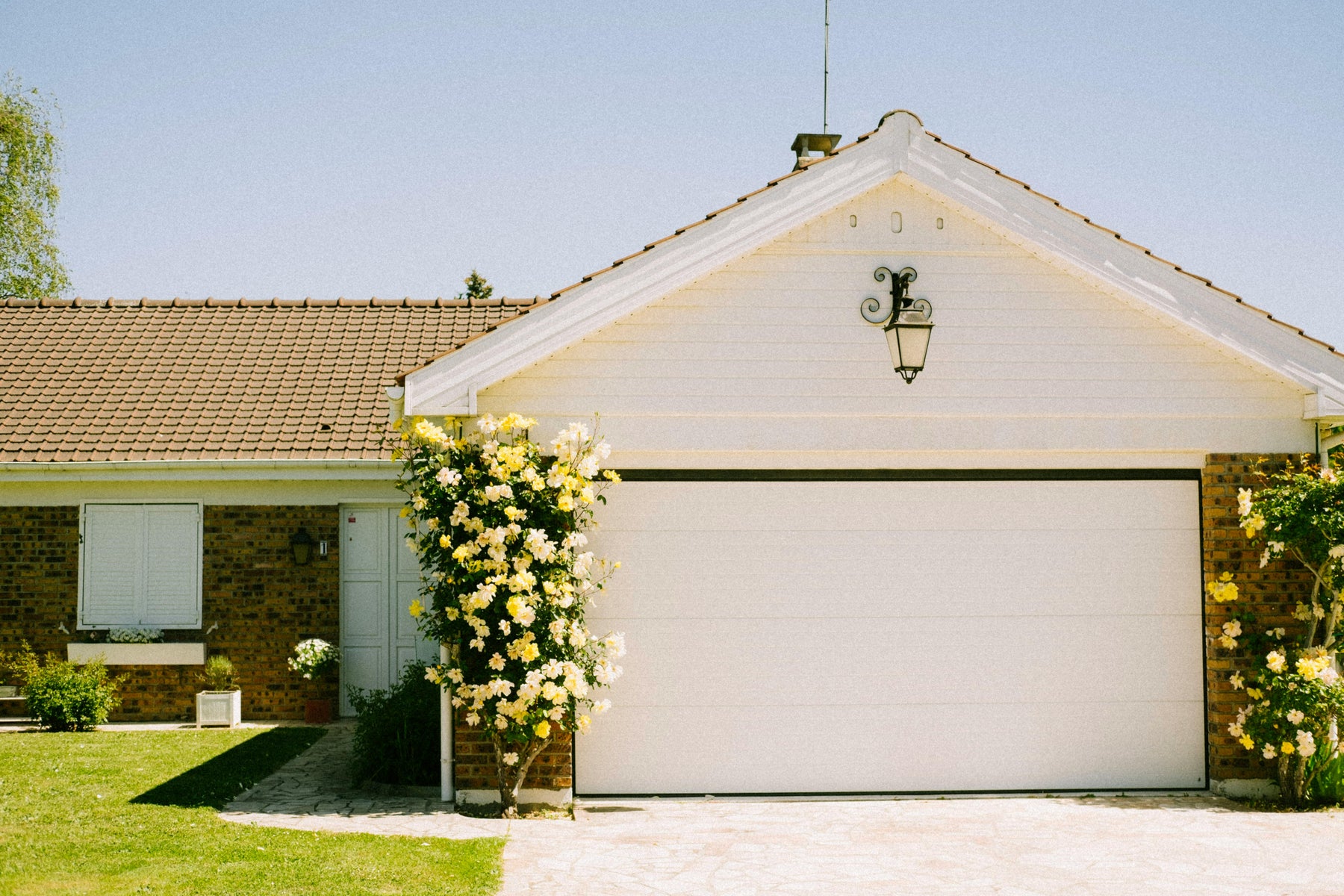 Brick house with two-car garage and yellow flowers.