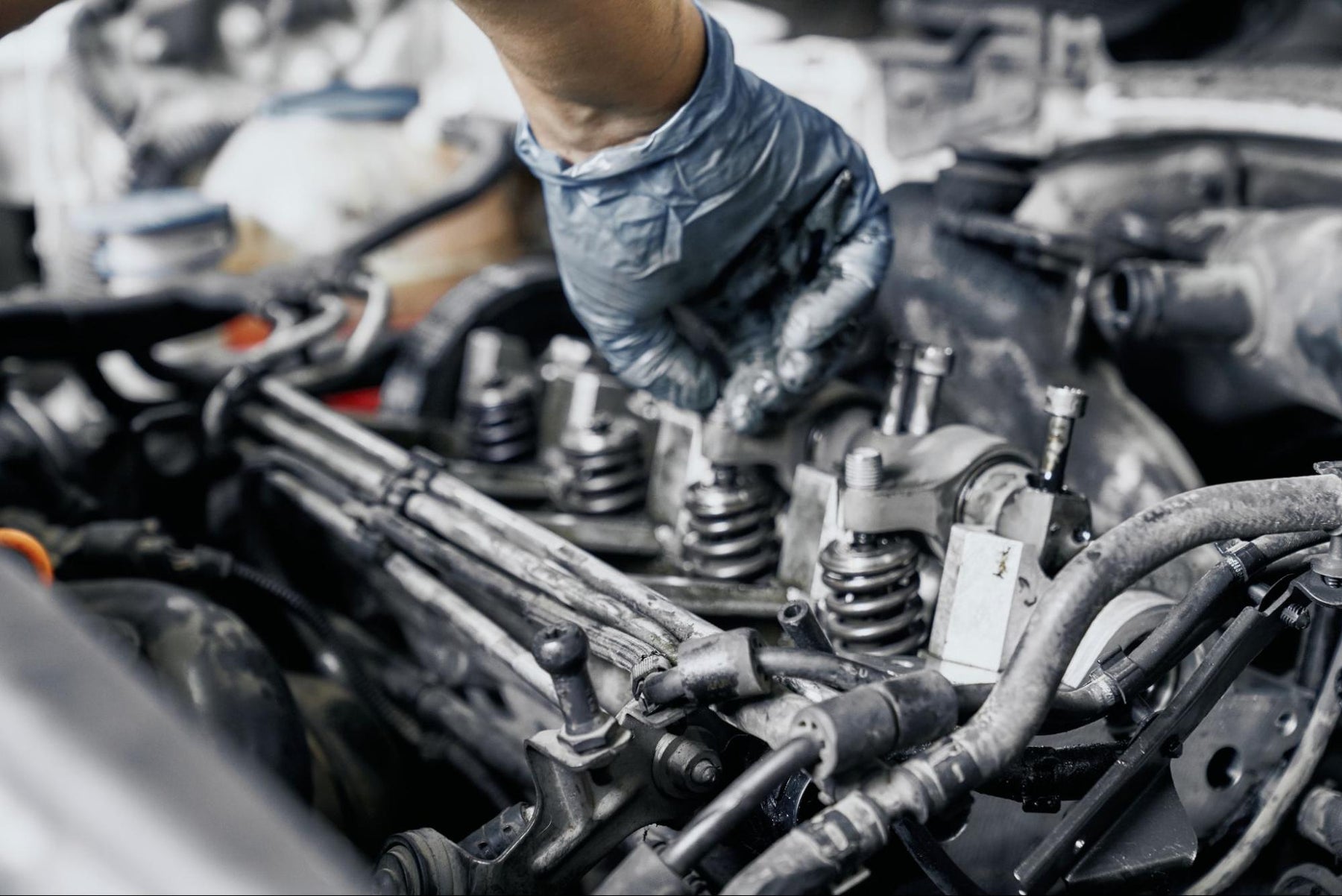 Mechanic in gloves performing detailed car engine inspection work.