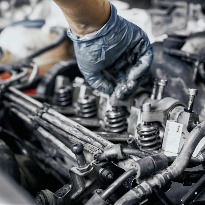 Mechanic in gloves performing detailed car engine inspection work.