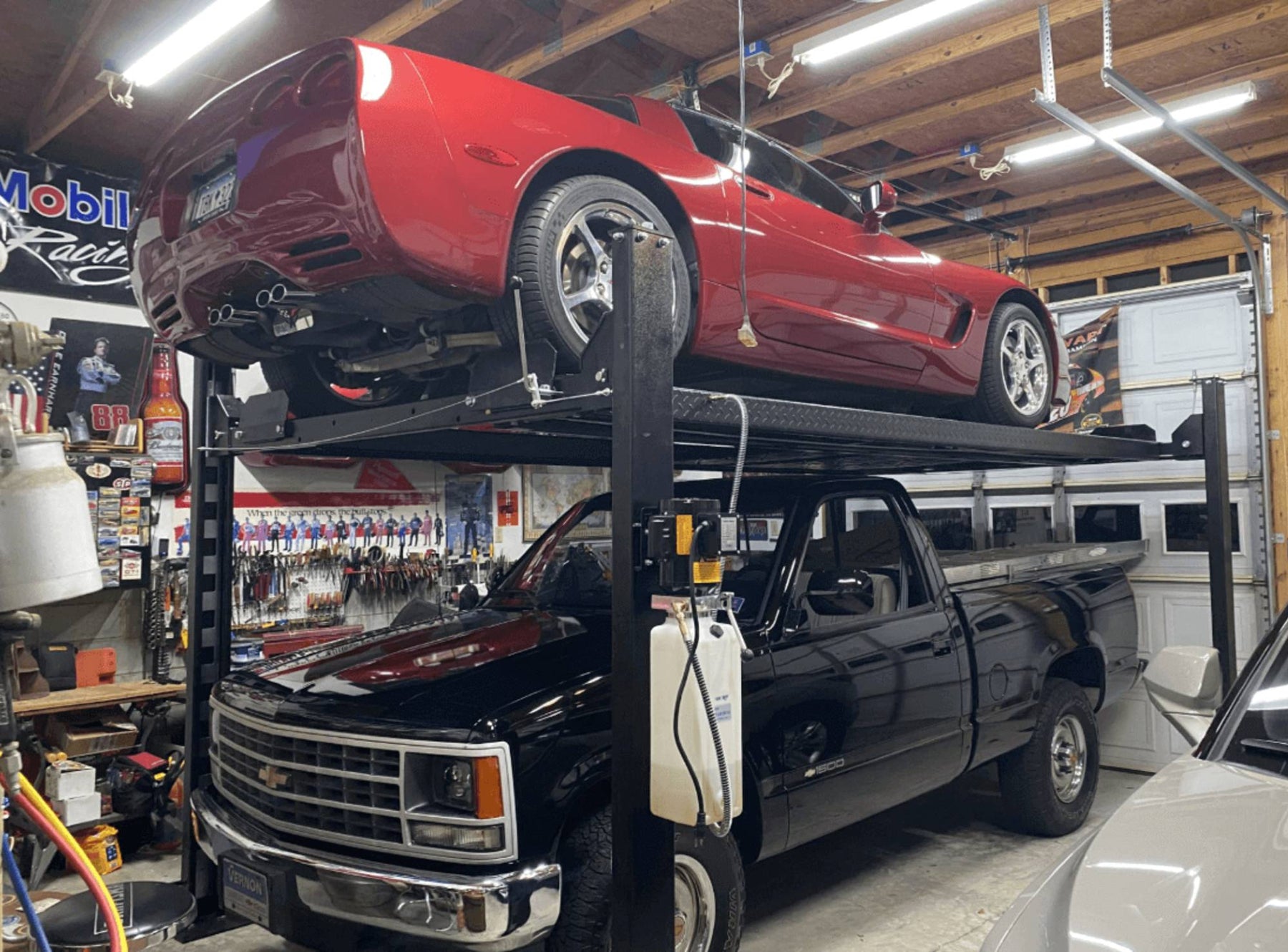 Corvette lifted above vintage Chevy truck in home garage.
