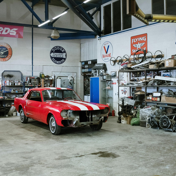 Red and white vintage car in a restoration garage workshop.