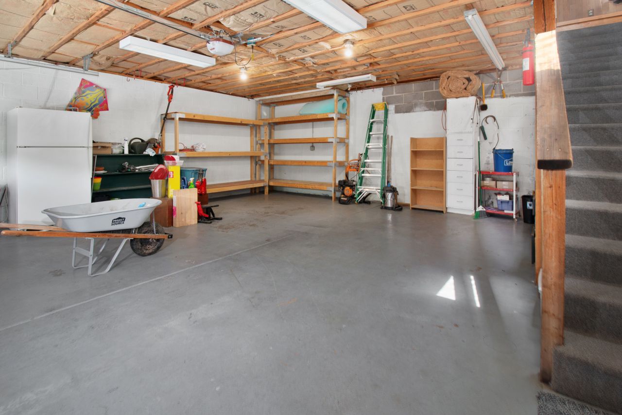 Spacious garage with shelves, tools, and concrete floor.