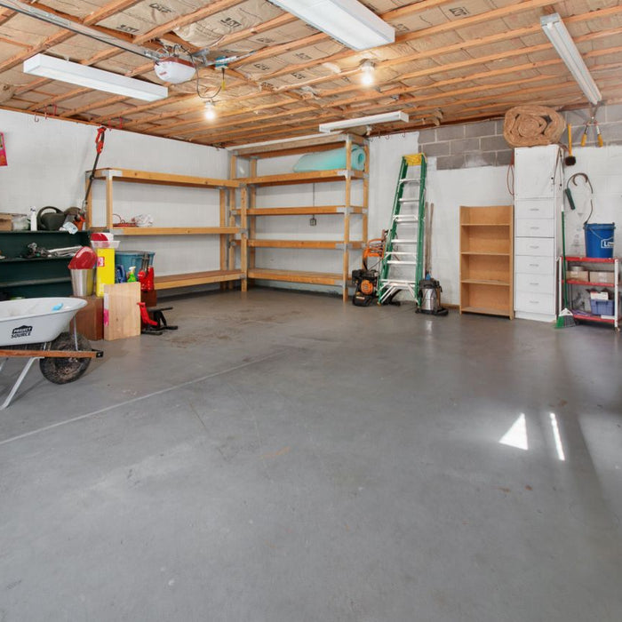 Spacious garage with shelves, tools, and concrete floor.