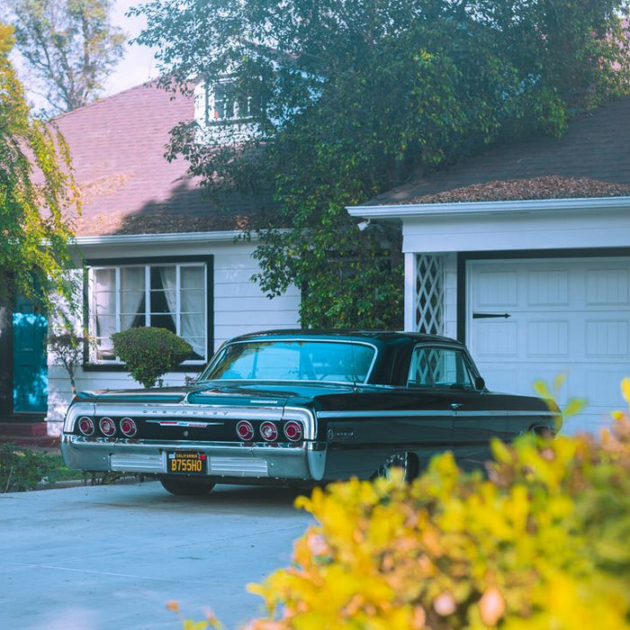Classic car parked in suburban driveway beside garage.