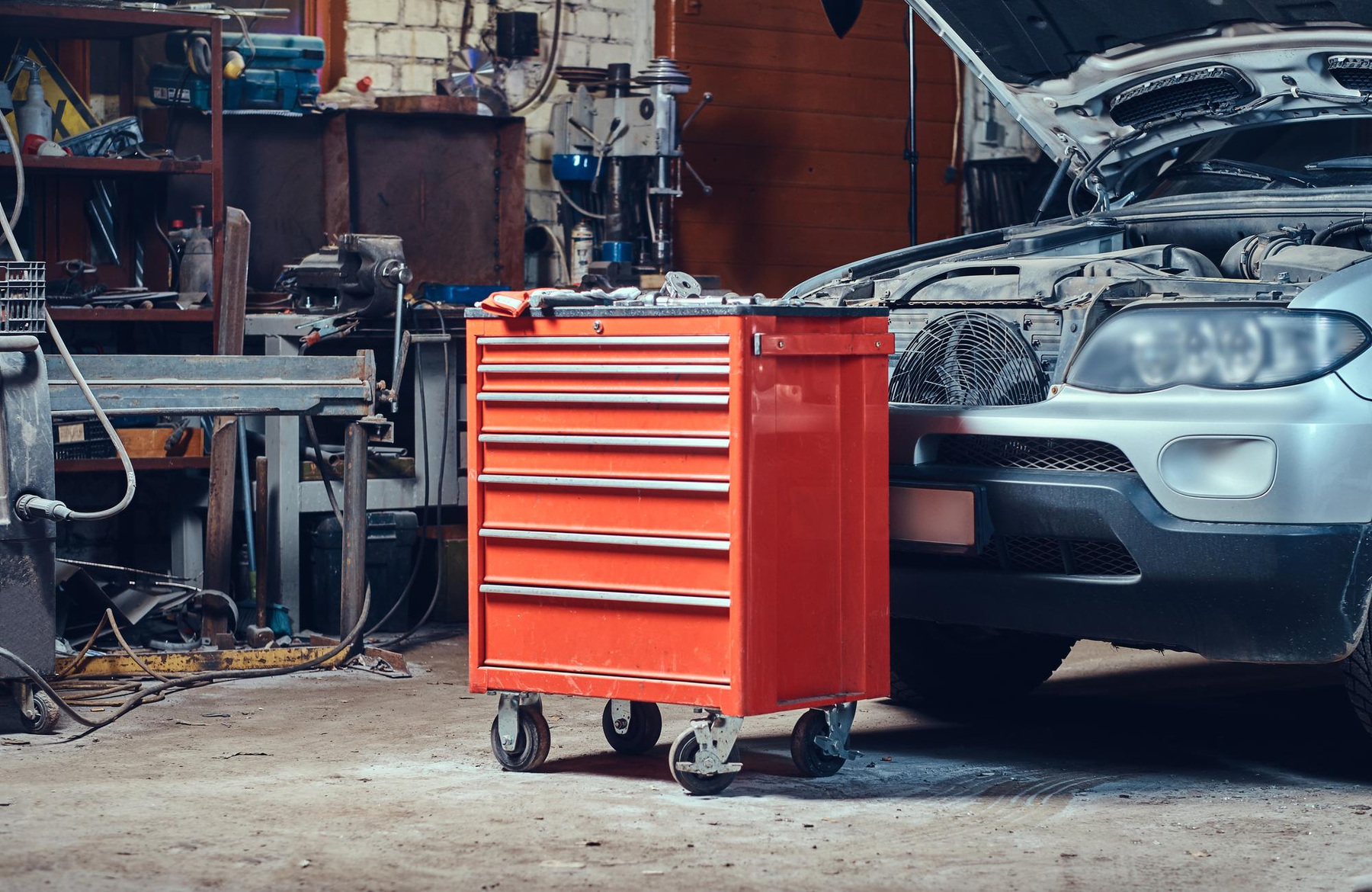 Red tool cabinet beside silver car in auto garage