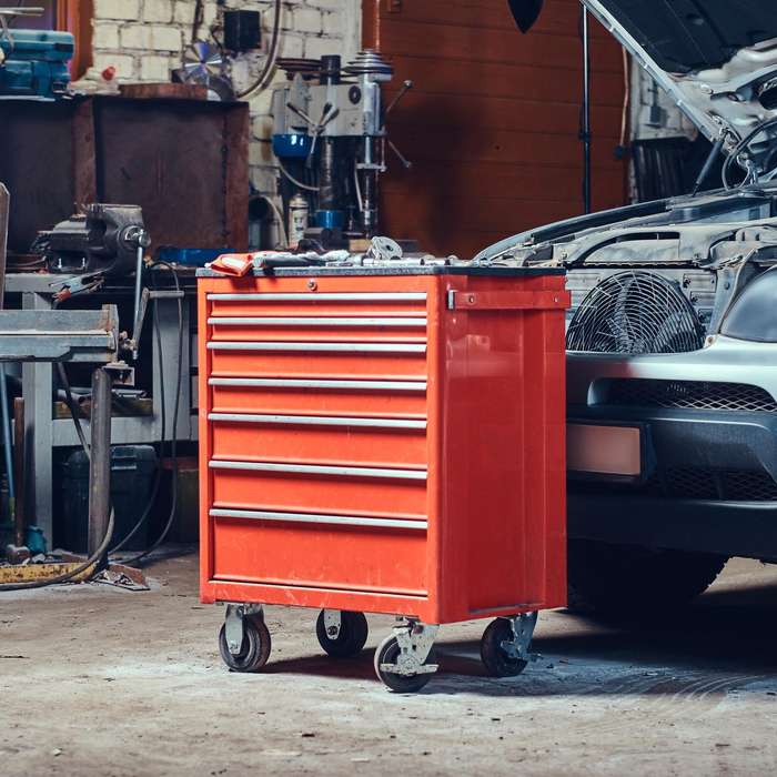 Red tool cabinet beside silver car in auto garage
